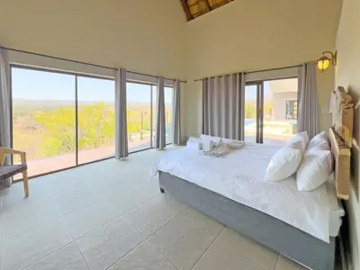 a bedroom with a large bed and large windows at Tebuah Private Lodge, Mabalingwe in Mabula