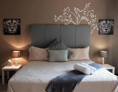 a bedroom with a large bed with two pictures on the wall at Goedehoop Boutique Manor House in Malelane