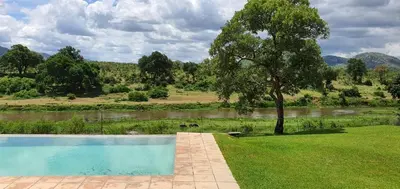 a swimming pool in the grass next to a river at Goedehoop Boutique Manor House in Malelane