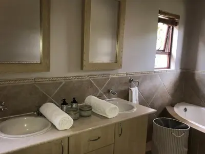 a bathroom with two sinks and a mirror at Goedehoop Boutique Manor House in Malelane
