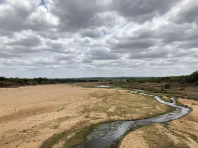 a river in the middle of a dirt field at Summerplace Holiday Home in Hazyview