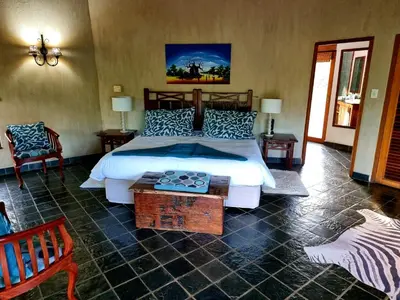 a bedroom with a large bed and two chairs at Sekala Private Game Lodge in Welgevonden Game Reserve