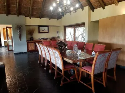 a dining room with a wooden table and red chairs at Sekala Private Game Lodge in Welgevonden Game Reserve