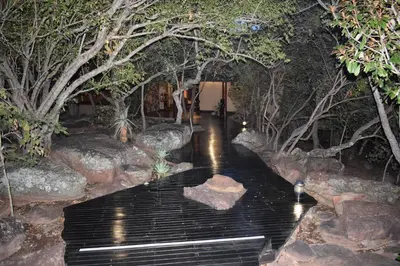 a bench in a garden with trees and rocks at Sekala Private Game Lodge in Welgevonden Game Reserve