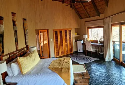 a bedroom with a bed and a table in it at Sekala Private Game Lodge in Welgevonden Game Reserve