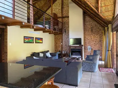 a living room with a couch and a table and a tv at Crocriver Chalet Schoemanskloof in Schoemanskloof