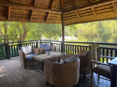 a wooden deck with chairs and a table on it at Crocriver Chalet Schoemanskloof in Schoemanskloof