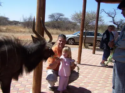 a man and a little girl feeding a goat at Makhato Bush Lodge 109 in Bela-Bela