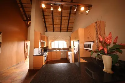a kitchen with wooden cabinets and a vase of flowers at Makhato Bush Lodge 109 in Bela-Bela