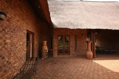a brick building with a straw roof and a patio at Makhato Bush Lodge 109 in Bela-Bela