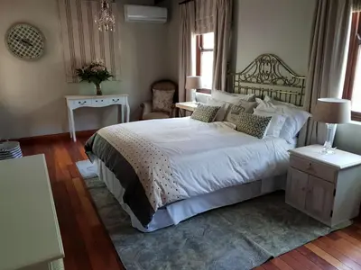 a bedroom with a large white bed and a table at Angel Oak guesthouse in Brits