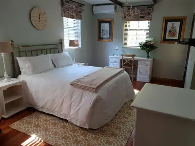 a bedroom with a bed and a table and two windows at Angel Oak guesthouse in Brits