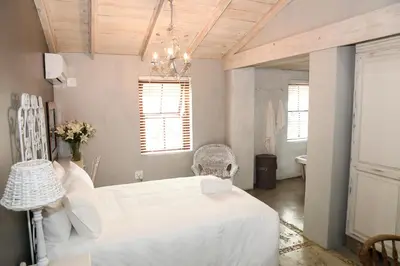 a bedroom with a white bed and a chandelier at Angel Oak guesthouse in Brits