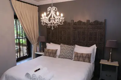 a bedroom with a large white bed with a chandelier at Angel Oak guesthouse in Brits