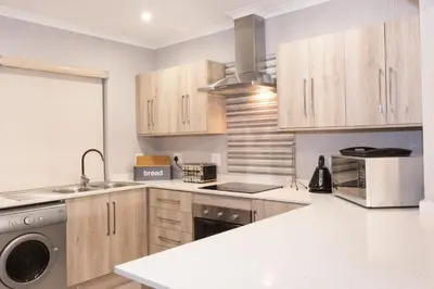 a kitchen with wooden cabinets and a sink and a dishwasher at Kruger Park Lodge Unit No. 611 in Hazyview