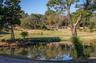 a man playing golf on a golf course next to a pond at Kruger Park Lodge Unit No. 612 in Hazyview