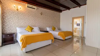 a bedroom with two beds with yellow and white sheets at See You There Accommodation 2 in Centurion