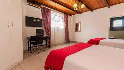 a bedroom with a bed and a desk and a chair at See You There Accommodation 2 in Centurion