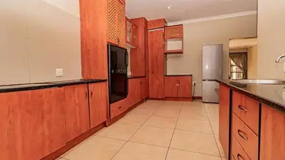 a large kitchen with wooden cabinets and a refrigerator at See You There Accommodation 1 in Centurion