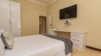 a bedroom with a white bed and a tv on the wall at See You There Accommodation 1 in Centurion