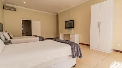 a bedroom with two beds and a tv on the wall at See You There Accommodation 1 in Centurion