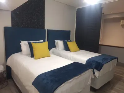 two beds with yellow and blue pillows in a room at See You There Accommodation in Centurion
