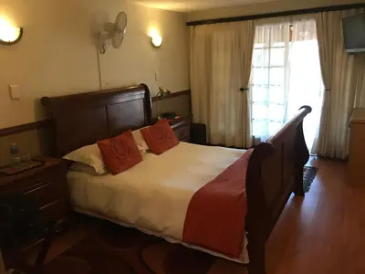 a bedroom with a bed with orange pillows and a window at De Oude Herberg in Centurion