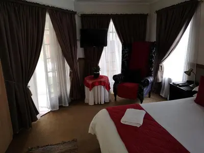 a hotel room with a bed and a chair and windows at De Oude Herberg in Centurion