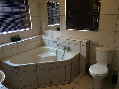 a bathroom with a bath tub and a toilet at De Oude Herberg in Centurion