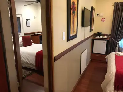 a room with two beds and a door to a bedroom at De Oude Herberg in Centurion