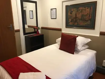 a bedroom with a white bed with a red pillow at De Oude Herberg in Centurion