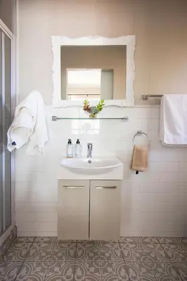 a white bathroom with a sink and a mirror at Willows Garden Studio in Pretoria