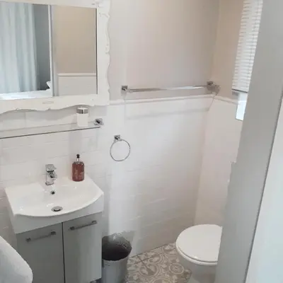 a white bathroom with a toilet and a sink at Willows Garden Studio in Pretoria
