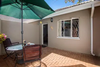 a patio with a table and a green umbrella at Willows Garden Studio in Pretoria