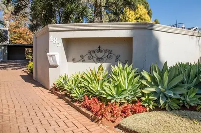 a wall with a gate in a garden with plants at Willows Garden Studio in Pretoria