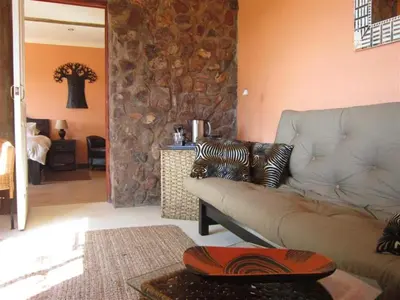 a living room with a couch and a stone wall at Marula Cottage Guest Lodge in Thabazimbi