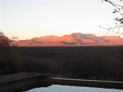 a swimming pool with a mountain range in the background at Marula Cottage Guest Lodge in Thabazimbi