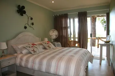 a bedroom with a bed with a white comforter at Marula Cottage Guest Lodge in Thabazimbi