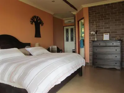 a bedroom with a large bed and a dresser at Marula Cottage Guest Lodge in Thabazimbi