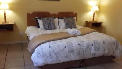 two beds in a hotel room with two lamps at The Old Mill Hotel in Machadodorp