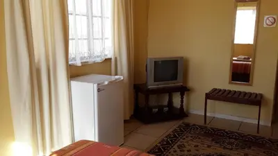 a room with a television and a small refrigerator at The Old Mill Hotel in Machadodorp