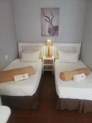 a room with three beds with towels on them at The Old Mill Hotel in Machadodorp