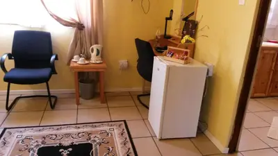 a kitchen with a white refrigerator and two chairs at The Old Mill Hotel in Machadodorp