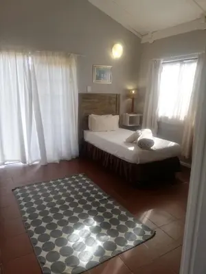 a bedroom with a bed and a black and white rug at The Old Mill Hotel in Machadodorp