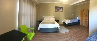 a room with two beds and a table and a chair at 4 on Sirius in Polokwane
