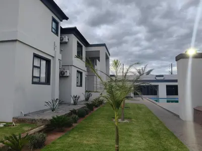 a white house with a palm tree in the yard at Sagwadi Hotel in Hazyview