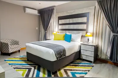 a bedroom with a large bed with yellow and blue pillows at Sagwadi Hotel in Hazyview
