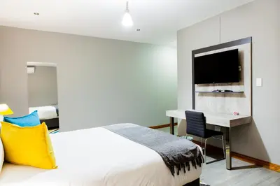 a bedroom with a bed and a desk and a television at Sagwadi Hotel in Hazyview