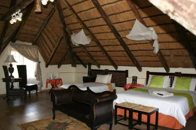 a bedroom with two beds and a chair in a room at Villa Royal Palm in Komatipoort