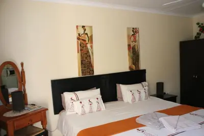 a bedroom with a bed with white sheets and pillows at Villa Royal Palm in Komatipoort